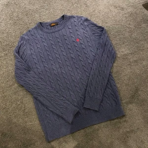 Mörkblå kabelstickad tröja från Morris - Säljer en stilren mörkblå kabelstickad tröja från Morris med ett rött broderat märke på bröstet. Nypris: 1600kr vs mitt pris: 499kr Tröjan är gjord av 100% Pima bomull och är helt nytt skick,  det är bara att skriva vid några funderingar svarar snabbt! Priset är inte hugget i sten🤩🔝😀