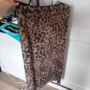 Leopardmönstrad kjol från Zara - Säljer en snygg leopardmönstrad kjol från Zara i bruna och beige toner. Kjolen har rak passform och är i en mjuk, stretchig syntetblandning. Perfekt för dig som vill sticka ut med ett djurmönster!