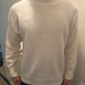 Vit stickad tröja - Säljer en enkel och stilren vit stickad tröja med rund hals och långa ärmar. Tröjan har ribbade muddar vid ärmslut, hals och nederkant. Använt en gång