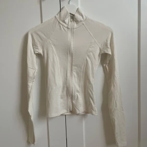 Vit zip-jacka från Gina Tricot - Säljer en vit, figurnära jacka från Gina Tricot med dragkedja framtill och hög krage. Jackan är långärmad och tillverkad i ett mjukt material som passar perfekt till lager-på-lager-stil. Knappt använd💗