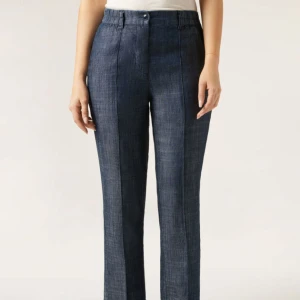 Palazzobyxor i linne och lyocell - Snygga palazzobyxor i blått med knappgylf och bälteshällor. Byxorna har elastisk midja och är gjorda i en mjuk blandning av linne och lyocell för extra komfort. Perfekta för en avslappnad och stilren look.