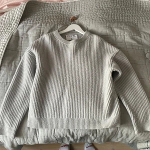 Ljusgrå stickad tröja från Filippa K - Säljer en stilren ljusgrå stickad tröja från Filippa K. Tröjan har rund halsringning, ribbad struktur och långa ärmar. 