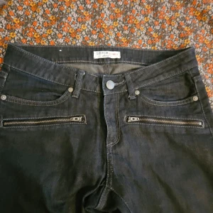 Svarta jeans med dragkedjor - Snygga svarta jeans från DR Denim med coola dragkedjor på framfickorna och vid bensluten. De har en tight passform och är perfekta för en stilren look. Jeansen har klassiska bakfickor och en knappgylf.