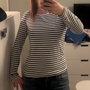Randig långärmad tröja i bomull - Säljer en klassisk långärmad tröja med svarta och vita ränder. Tröjan har rund halsringning och är i mjuk bomull, perfekt för en enkel och stilren look. Passar till jeans eller kjol för en avslappnad stil. 💗