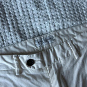Vita byxor från John Henric - Snygga vita byxor från John Henric med en klassisk design. De har en knapp och dragkedja framtill samt fickor både fram och bak. Perfekta för en stilren look.