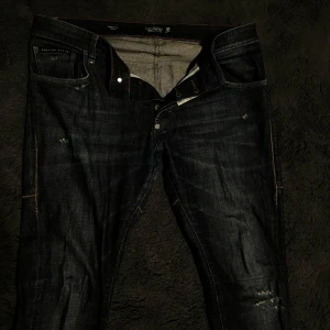 Philipp Plein jeans - Snygga Philipp Plein jeans i mörkblå denim med straight cut och låg midja. Byxorna har klassiska fem fickor och en diskret logga på bakfickan. Tillverkade i Italien med en blandning av bomull och elastan för extra komfort.