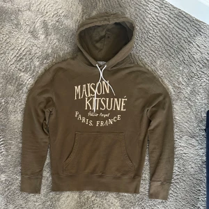 Maison kitsune hoodie - Säljer en snygg mörkgrön/brun hoodie från Maison kitsuné. Den är i bra skick och har inga defekter. Är öppen för byten✅Hör av er vid minsta fundering🙂