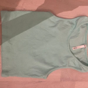Mintgrön ribbad linnetopp från NEU - Säljer en fräsch mintgrön ribbad linnetopp från NEU. Perfekt för varma dagar med sin ärmlösa design och mjuka material. Toppen har en enkel och stilren look som passar till det mesta. Hör av dig vid intresse! 💕💕