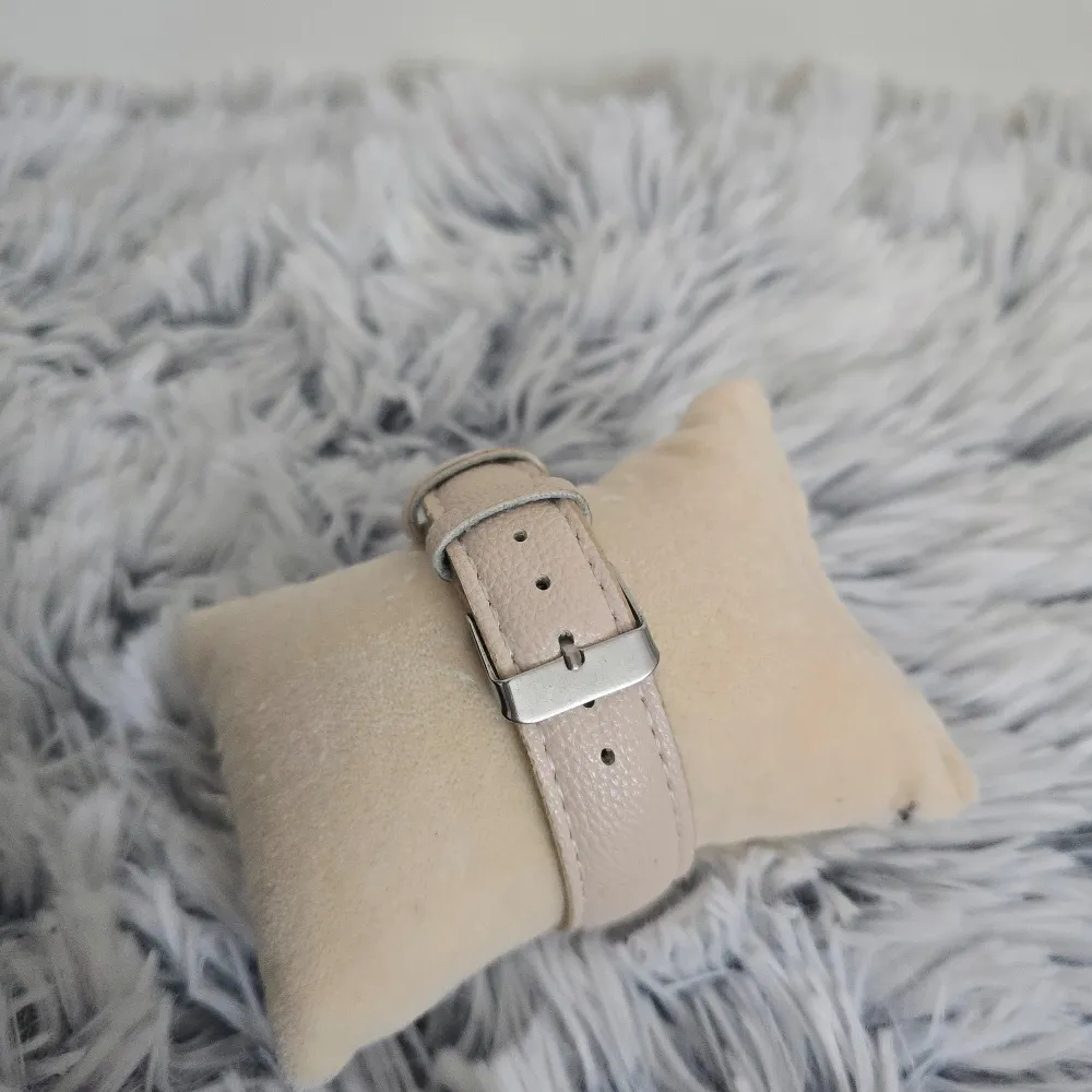 Snygg klocka med beige skinnarmband och en urtavla prydd med ett ankare och rosa blommor. Boetten är i guld och ger en elegant touch. Perfekt för den som gillar marina teman och stilrena accessoarer.. Asusteet.