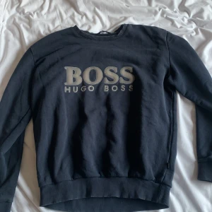 Svart sweatshirt från Hugo Boss - Säljer en stilren svart mörkblå från Hugo Boss med logotyp i silver på bröstet. 