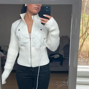 Vit quiltad jacka med dragkedja - Säljer en snygg vit jacka med quiltade detaljer och dragkedja. Jackan har långa ärmar och en ribbad design som ger en tight passform. Perfekt för kyligare dagar när du vill ha snygg outfit❤️
