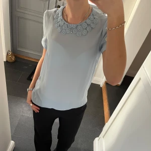 Blå topp med blommor - Blå kortärmad blus från Mint & Berry i storlek 36. Fint skick. Lite genomskinlig. Använd gärna köp nu!