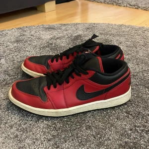 Nike Air Jordans i rött och svart - Säljer ett par klassiska Nike Air Jordans i rött och svart. Skorna har en snygg design med svart snörning. Perfekta för dig som älskar en sportig stil. Lite slitna vid sko snörena.