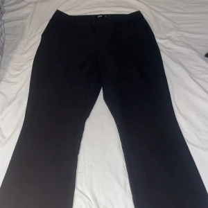 Svarta kostymbyxor från BikBok - Snygga svarta kostymbyxor från BikBok i storlek 46. Byxorna har en klassisk design med rak passform och är perfekta för en stilren look. De är tillverkade i ett bekvämt material som ger en elegant känsla. Jag är 171 cm och byxorna går hela vägen ner till o med under mina fötter