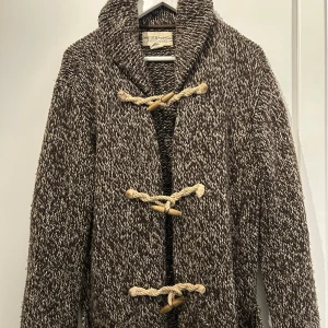 Ralph Lauren Stickad Ull Cardigan - Säljer en snygg ull stickad tröja från Ralph Lauren i storlek (M) med unika knappar i repdesign. Tröjan har en mysig krage och långa ärmar, perfekt för kyligare dagar. Inga defekter (10/10 skick!)🔥Perfekt för dig som vill ha en stilren och bekväm look.