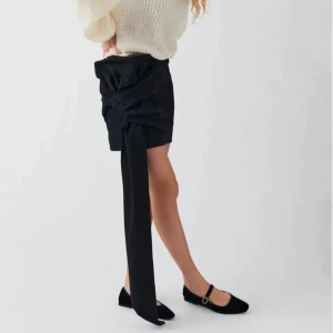 Denim skirt - Gina Tricot - Trendig svart kortkjol med en unik knytning på sidan som ger en cool look. Perfekt för att sticka ut på festen eller andra tillfällen. Kjolen har en stilren design och är lätt att matcha med olika toppar. Aldrig använd och har prislapp kvar!