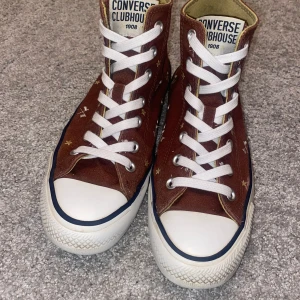Converse skor  - Snygga bruna Converse med vita snören och stjärndetaljer. Klassisk hög modell. De är i bra stick de har bara små hålar in i skor men det märks inte. 