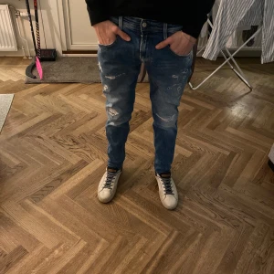 Blå jeans med slitningar från replay - Snygga blå jeans med slitningar och en avslappnad look från replay. Perfekta för en casual stil. De har en normal passform och är midwaist, vilket gör dem bekväma att bära hela dagen.