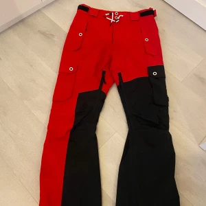  Dope Skidbyxor  - Snygga röd-svarta byxor från Dope med flera praktiska fickor och justerbar midja. Perfekta för utomhusaktiviteter med sin tåliga design och coola look. Endast använda två veckor😍 Passar även mig som har storlek S då dem är något stora.