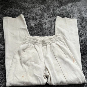 Beige mjukisbyxor - Bekväma beige mjukisbyxor med elastisk midja och raka ben. Perfekta för en avslappnad stil. Byxorna har fickor på sidorna för extra funktionalitet.