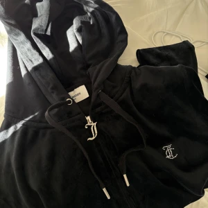 Hoodie och byxor från Juicy Couture - Säljer en svart velour hoodie och matchande byxor från Juicy Couture. Hoodien har en dragkedja och glittrande Juicy-logga på ryggen. Byxorna har en elastisk midja och samma glittrande logga på baksidan. 1000 för båda, 500kr styck.