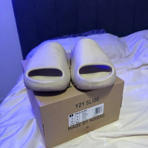 Yeezy Slide ”Bone” - Säljer ett par bekväma och stilrena Yeezy Slide Bone. Perfekta för en avslappnad look med en modern touch. Dom är i bra skick för att dom har använts lite. Pris kan diskuteras!