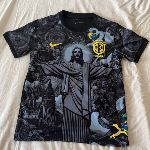 Svart Brasilien fotbollströja från Nike - STORLEK M. Snygg fotbollströja från Nike med Brasilien som logga och jesus i mitten. Väldigt trendig tröja som många verkligen gillar. Jätte bekväm och perfekt inför sommaren. PRISET KAN DISKUTERAS.