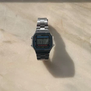 Casio A168 vintage watch - Säljer en digital Casio A168-klocka, köpt från Klockmagasinet.se för 500 kr, nu till salu för 299 kr. Klockan är i fint skick och har bara använts 3-5 gånger. Alla funktioner fungerar perfekt. Den är vattentålig och tillverkad av rostfritt stål. Klockan har tre knappar för enkel justering av tid och inställningar. Armbandet är justerbart och passar de flesta handleder. Klockan kommer i original boxen. Kontakta mig gärna om du har några frågor eller vill ha fler bilder.