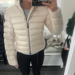 Beige dunjacka från Colmar - Säljer en snygg beige dunjacka från Colmar med dragkedja och huva. Jackan har en normal passform och är perfekt nu till våren. Storlek 44 (colmars egna storlekar, kolla deras hemsida för rätt storlek, jag är storlek S för referens ). Köpt för några månader sen, aldrig använd, nypris 5000