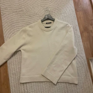 Vit stickad tröja från Gina Tricot - Säljer en stilren vit stickad tröja från Gina Tricot. Tröjan har en rund halsringning och långa ärmar med ribbade muddar vid ärmslut och nederkant. Perfekt för en mysig och avslappnad look. Snålt använd 