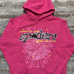 Spider hoodie Pink - Cool rosa hoodie från Not in the World med ett stort spindelnätmönster och text i svart och vitt på framsidan. Perfekt för en avslappnad stil med en touch av attityd. 🕸️