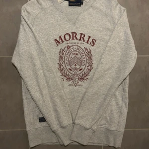 Grå sweatshirt från Morris R Club - Säljer en stilren grå sweatshirt från Morris R Club med ett snyggt tryck i vinrött på framsidan. Tröjan har långa ärmar och en rund halsringning. Perfekt för en avslappnad stil. 🛍️