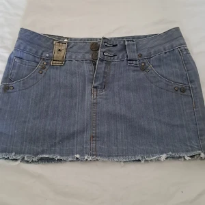 Grå jeans kjol med ränder - Jättefin classic jeanskjol. Med många detaljer och randig. Kjolen är rätt så kort. Köpt från en marknad i Thailand.