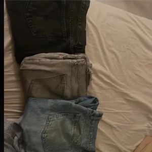 Tre par jeans i olika färger - Säljer tre par jeans i olika färger: ett par svarta, ett par gråa och ett par ljusblå. Alla har klassisk femficksdesign och raka ben. Perfekta för dig som vill ha lite variation i garderoben och gillar avslappnad stil.
