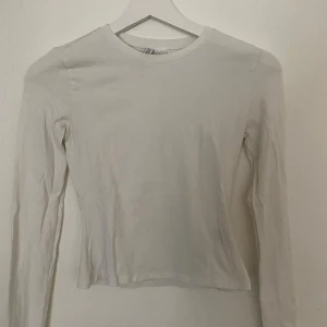 Vit långärmad tröja från H&M Divided - En enkel och stilren vit långärmad tröja från H&M Divided, modell Basic. Tröjan har rund halsringning och är tillverkad i mjuk bomull som är skön mot huden. Passformen är normal och den är perfekt att matcha med jeans eller kjol för en clean look.