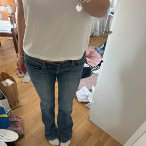 American eagel jeans  - Säljer ett par blå bootcut jeans från american eagel med låg midja och klassisk femficksdesign. Jeansen har snygga kontrastsömmar och ett broderat märke på bakfickan. Materialet är mjukt denim i bomull med lite stretch för skön passform.