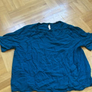 Blå blus från Å med kort ärm - Säljer en snygg blå blus från Å i storlek 44. Blusen har korta ärmar och en enkel, avslappnad passform. Materialet känns lätt och luftigt, perfekt för varmare dagar. Rund hals med liten öppning bak. Passar dig som gillar stilren och enkel design.