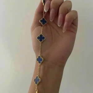 Blå och guldigt armband med klöver - Snyggt armband med blåa fyrklöverformade hängen infattade i guldfärgad metall. Rostfritt stål!