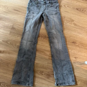 Grå bootcut jeans från Gina Tricot - Snygga grå jeans från Gina Tricot i storlek 158. Modellen har bootcut-ben och raka sömmar framtill, med stora fickor både fram och bak. Jeansen är gjorda i ett klassiskt denimtyg och har en cool, lite tvättad look.