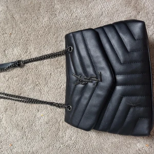 Svart quiltad axelväska  - Snygg svart axelväska, köpt på en marknad i Spanien så den är tyvärr ej äkta men ser väldigt bra ut! Den är aldrig använd och köpt för 600 kr därav säljer jag den för 500, men pris kan diskuteras vid en snabb affär😇