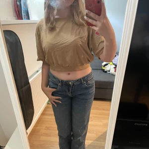 Beige croppad topp från 157 - Säljer en beige croppad topp från 157 med rund hals och korta ärmar. Toppen har loose passform och är tillverkad i mjuk bomull. Perfekt för dig som gillar chill och enkel stil. Resår nedtill ger en snygg siluett och gör den extra bekväm.