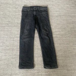 Svarta jeans från Replay Thad - Storlek 152 barn!!! Säljer ett par svarta Replay Thad jeans med klassisk femficksdesign och raka ben. Jeansen har en mörk tvätt och snygga detaljer vid fickor och midja. Materialet är slitstarkt denim som sitter skönt och passar till många olika stilar. Priset är inte hugget i sten