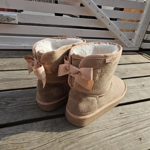 Uggs - Ett par beigea uggs med rosett bak i storlek 37. Som nya sällan använda!