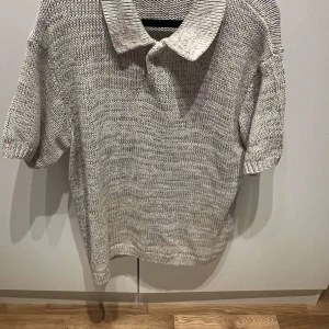 Stickad pikétröja från Zara i beige - Säljer en stickad pikétröja från Zara i beige ton. Tröjan har korta ärmar, klassisk krage och är tillverkad i ett grovt stickat material som ger en chill och avslappnad vibe. Perfekt för dig som gillar en enkel men snygg look.