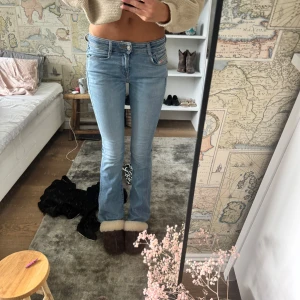 Bootcut ljusblå jeans från Diesel  - Säljer ett par ljusblå bootcut jeans från Diesel med klassisk femficksdesign och låg midja. Jeansen har en snygg passform som sitter tajt över låren och släpper ut vid bensluten. Materialet är mjukt denim och de har Diesel logga på fickan.