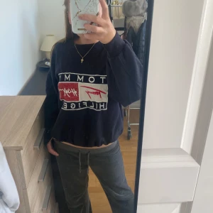 Mörkblå Tommy Hilfiger sweatshirt - Mörkblå sweatshirt från Tommy Hilfiger med stort tryck på bröstet i vitt och rött. Tröjan har en loose passform och långa ärmar, perfekt för chill dagar. Materialet är mjuk bomull och polyesterblandning. Snygg att matcha med jeans eller mjukisbyxor.