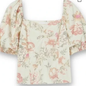 Blommig linnetopp från H&M - Supersöt topp från H&M i linnemix med blommigt mönster i ljusa toner av rosa, beige och grön. Modellen har puffiga korta ärmar, fyrkantig ringning och smickrande passform💕