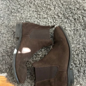Bruna mocka chelsea boots - Snygga bruna chelsea boots i mocka från märker ”these glory days” Perfekta skor till de kallare årstiderna! Hör av dig om du vill ha fler bilder eller diskutera om priset !