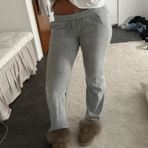 Grå mjukisbyxor från Juicy Couture XS - Grå mjukisbyxor från Juicy Couture med snörning i midjan och fickor både fram och bak. Byxorna har broderad logga på ena fickan och är gjorda i mjukt bomullsmaterial, perfekta till hösten! Nypris 1100kr. Köparen står för frakten!