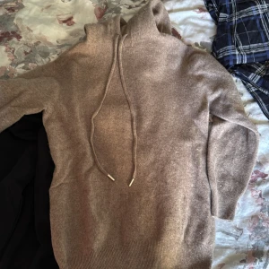 Beige kashmir hoodie - Mysig beige stickad hoodie med huva och långa ärmar. Tröjan har snörning vid halsen och ribbade muddar vid ärmslut och nederkant. Perfekt för dig som gillar en chill och avslappnad stil. I stl xxs till xs